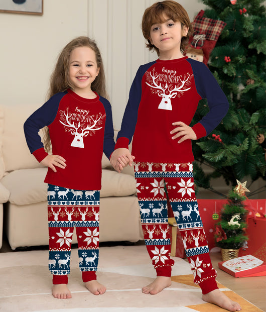 Child wearing a red and navy blue Christmas pajama set with a white reindeer and "happy NEW YEAR" text on the top, and fair isle pattern pants. - Image 6