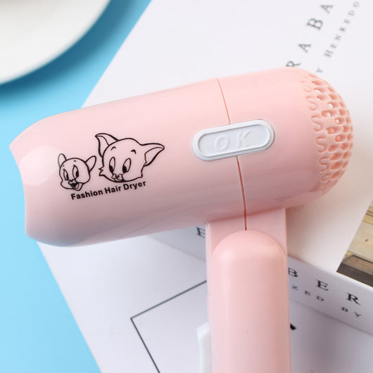 Light blue foldable hair dryer with a cartoon pig design, white power switch, and hanging loop. - Image 3