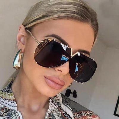 Oversized V-shaped sunglasses with a gold metal frame, white accents, clear lenses, and decorative rivets. - Image 2