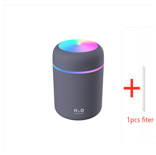 Dark gray cylindrical humidifier with colorful LED top light and thin light band, shown with five white filter sticks.