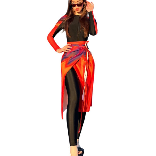Woman in a black long-sleeve rash guard, black swim leggings, and a vibrant tie-dye sarong on a sunny beach. - Image 5