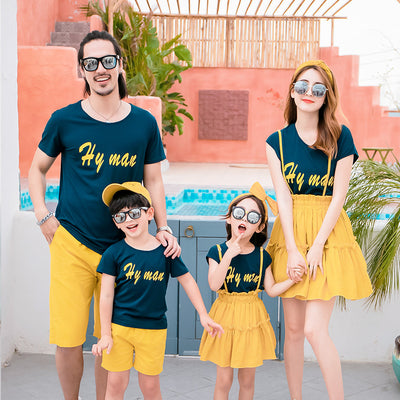 Family of four in matching dark blue short-sleeved tops with yellow text and yellow bottoms, posing outdoors. - Image 12