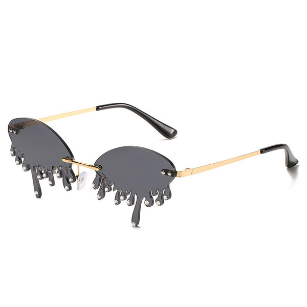 Rimless sunglasses with dark gray dripping liquid-shaped lenses, silver studs, and gold metal frames. - Image 3