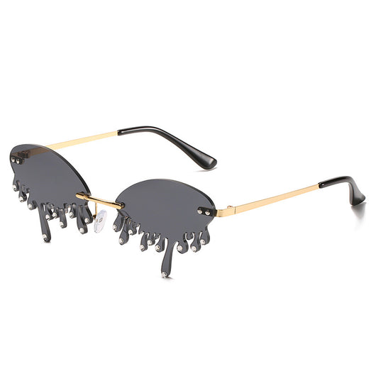 Rimless sunglasses with dark gray dripping liquid-shaped lenses, silver studs, and gold metal frames. - Image 3