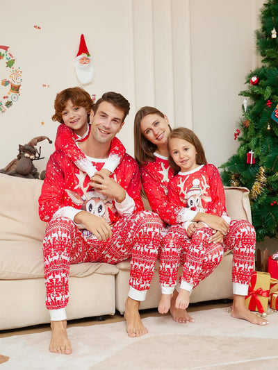 Family of four wearing matching red Christmas pajamas with reindeer and snowflake patterns, sitting on a sofa. - Image 12