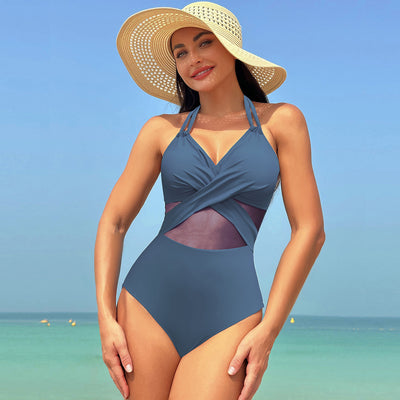 Woman in a green halter-neck one-piece swimsuit with cross-strap design and mesh cutouts, on a beach. - Image 7