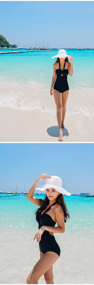 Woman wearing a taupe ribbed one-piece swimsuit with a halter neckline and twisted bust detail on a sandy beach. - Image 17