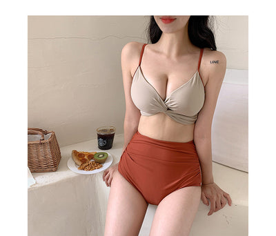 Woman in a blue twisted triangle bikini top and white high-waisted bottoms, holding a leaf-print cover-up. - Image 11