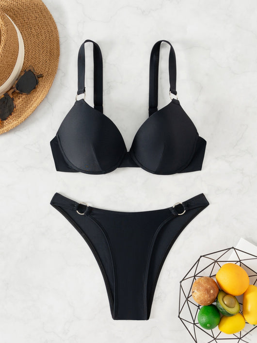 Woman in a black pure color bikini with gold O-rings, featuring a push-up top and high-cut bottoms, by the ocean. - Image 8