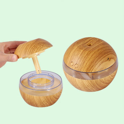 Spherical wood grain humidifier with a clear band, emitting mist, against a dark background with lotus flowers. - Image 3