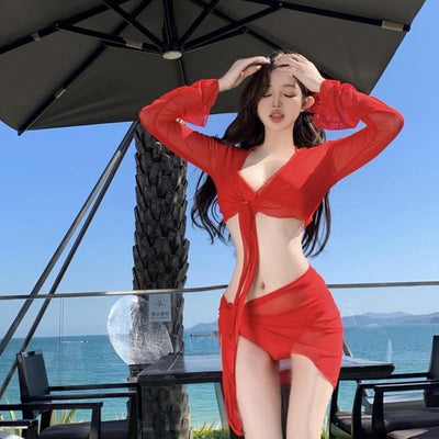 Red four-piece bikini set with sheer long-sleeve tie-front top and matching tie-front skirt on a beach. - Image 11