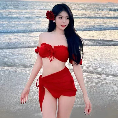 Woman in a red strapless ruffled bikini top and matching sarong on a beach at sunset.