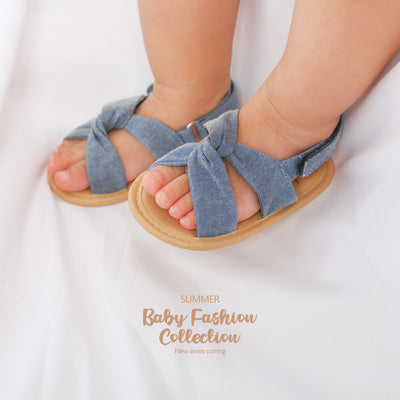 Black baby sandals with knotted cross straps and a matching black floral headband on a white background. - Image 26