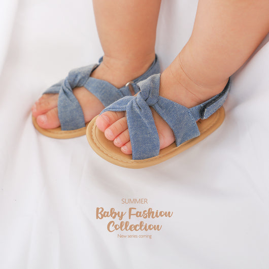 Black baby sandals with knotted cross straps and a matching black floral headband on a white background. - Image 26