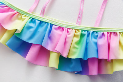 Children's rainbow tie-dye bikini set with a ruffled top and side-tie bottoms, perfect for summer swimming. - Image 3