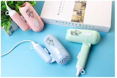 Light blue foldable hair dryer with a cartoon pig design, white power switch, and hanging loop. - Image 10