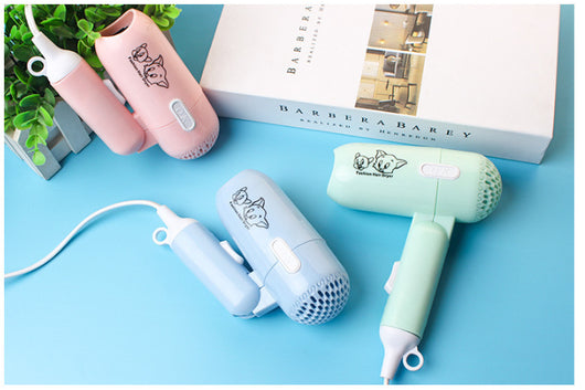 Light blue foldable hair dryer with a cartoon pig design, white power switch, and hanging loop. - Image 10