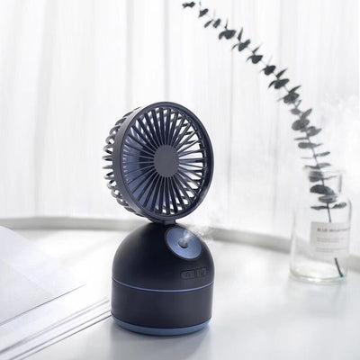 Dark grey fan humidifier with a round fan head and spherical base, emitting mist, on a white desk. - Image 7
