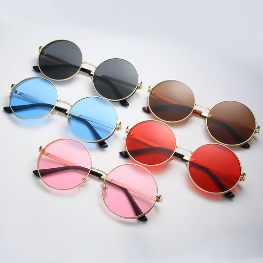 Round gold metal frame sunglasses with brown lenses and glitter detail on the outer rim, featuring dark red temple tips.