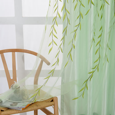 Light green sheer curtains with a delicate willow leaf print, hung on a window rod in a bright room.