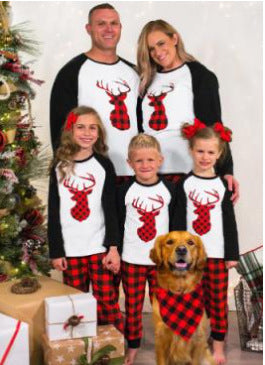 Family of four and golden retriever in matching red and black plaid deer Christmas pajamas, by a decorated tree. - Image 6