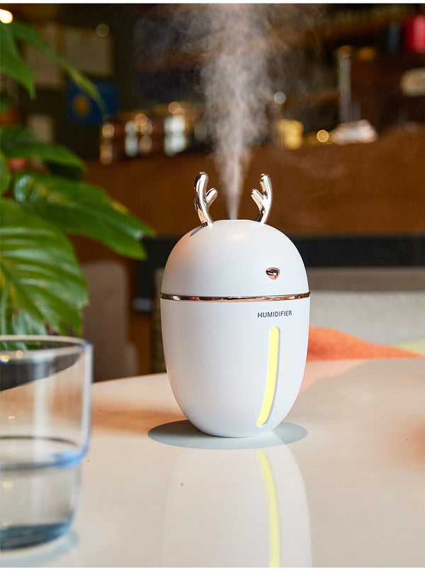 Pink deer-shaped ultrasonic humidifier with gold antlers, a white USB fan, and a white USB light.