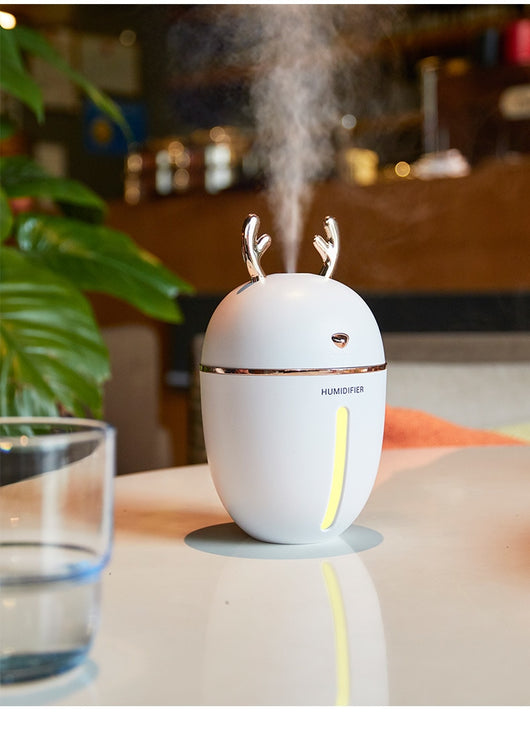 Pink deer-shaped ultrasonic humidifier with gold antlers, a white USB fan, and a white USB light.