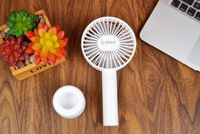 White ORICO FH1 handheld USB fan with charging dock, USB cable, and user manuals on a wooden desk. - Image 4