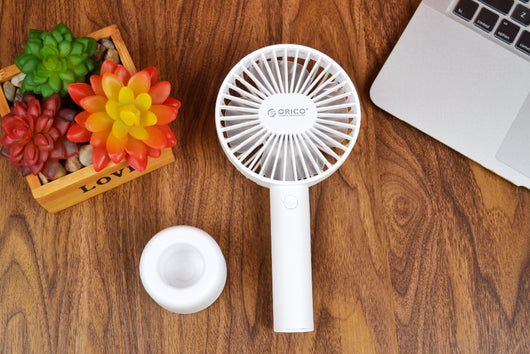 White ORICO FH1 handheld USB fan with charging dock, USB cable, and user manuals on a wooden desk. - Image 4