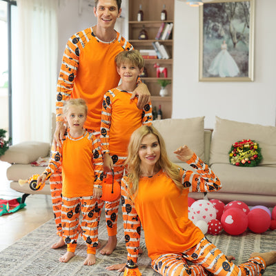 Family of four wearing matching orange and white striped Halloween pajamas with pumpkin and bat prints. - Image 5