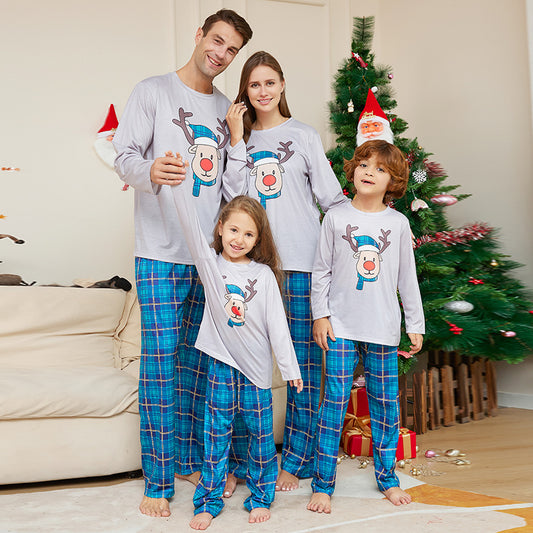 Young girl wearing a grey long-sleeve pajama top with a cartoon reindeer and blue plaid pajama pants.