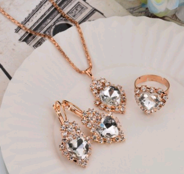 Rose gold-toned necklace, earrings, and ring set with large oval clear gemstones surrounded by smaller stones. - Image 14