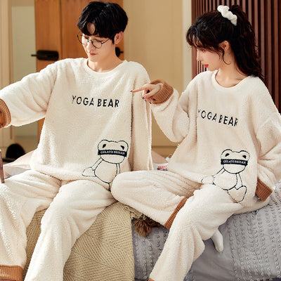 Couple wearing matching cream coral fleece pajamas with gray pants and bear embroidery, seated on a bed. - Image 7