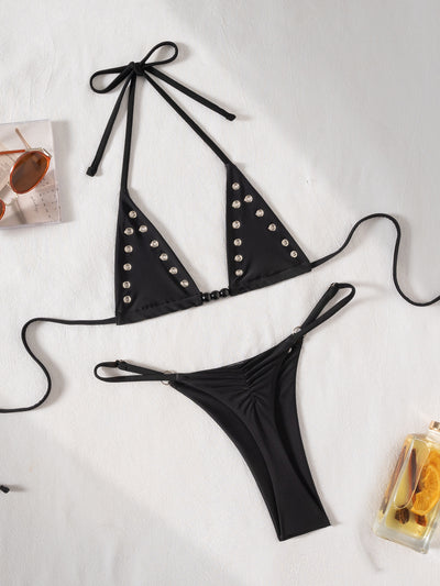 Black tie-front bikini swimsuit with silver grommets on the triangle top and a ruched thong bottom, laid flat. - Image 15