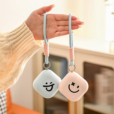 Light green square hand warmer with rounded corners and a black smiley face, hanging from a two-tone lanyard. - Image 4