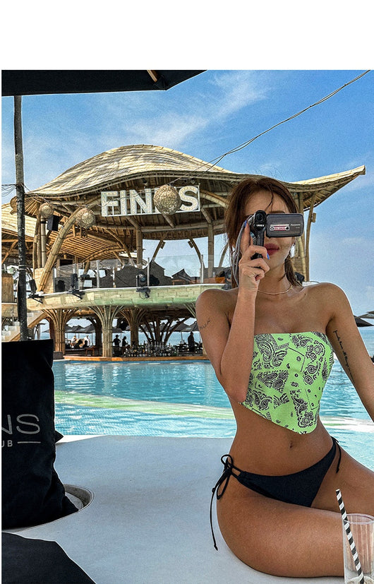 Lime green bandana print bandeau bikini top with black low-rise tie-side bottoms on a woman by a pool. - Image 11