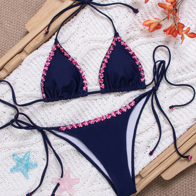 Navy blue bikini swimsuit set with pink floral lace trim on triangle top and tie-side bottoms, on a white knit blanket. - Image 4