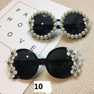 White round sunglasses with daisy flower embellishments on the frames and dark gradient lenses.