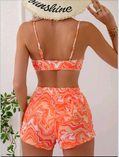 Red, orange, and white abstract swirl print three-piece bikini set with matching shorts, shown with a straw hat and sunglasses. - Image 18