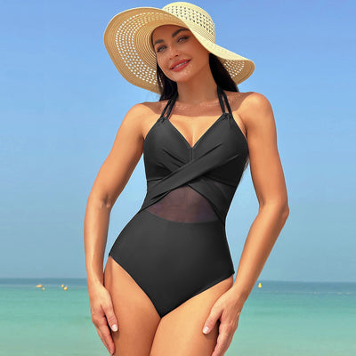 Woman in a green halter-neck one-piece swimsuit with cross-strap design and mesh cutouts, on a beach. - Image 5