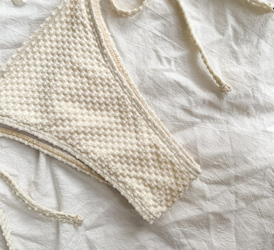White halter lace-up bikini with a textured pattern, styled with a straw hat and gold jewelry on a sandy background. - Image 2