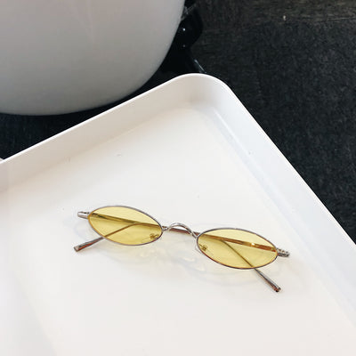 Silver-framed oval sunglasses with dark lenses reflecting a warm-toned object, displayed on a white tray. - Image 4