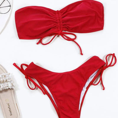 Red two-piece bikini with a strapless ruched bandeau top and matching side-tie bottoms, displayed on a white surface. - Image 3