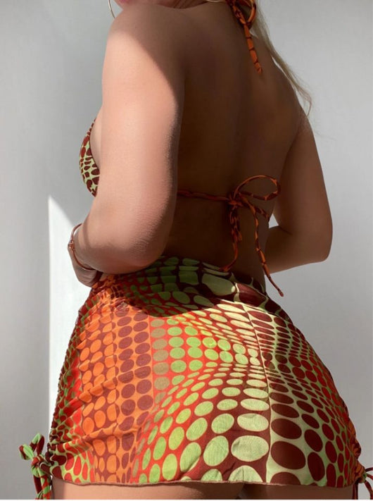 Women's printed split bikini swimsuit set with halter top, high-cut bottom, sarong skirt, and headscarf in green, brown, and orange optical dot pattern. - Image 8
