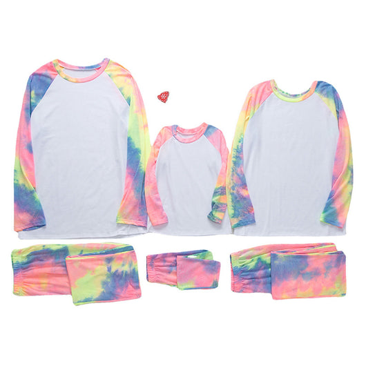 Family of four wearing matching pink, blue, and yellow tie-dye long-sleeved pajama sets in a living room. - Image 4