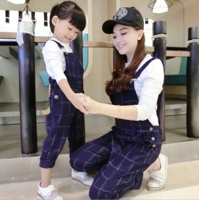 Mother and child wearing matching navy blue plaid overalls with white long-sleeve shirts, holding hands. - Image 12
