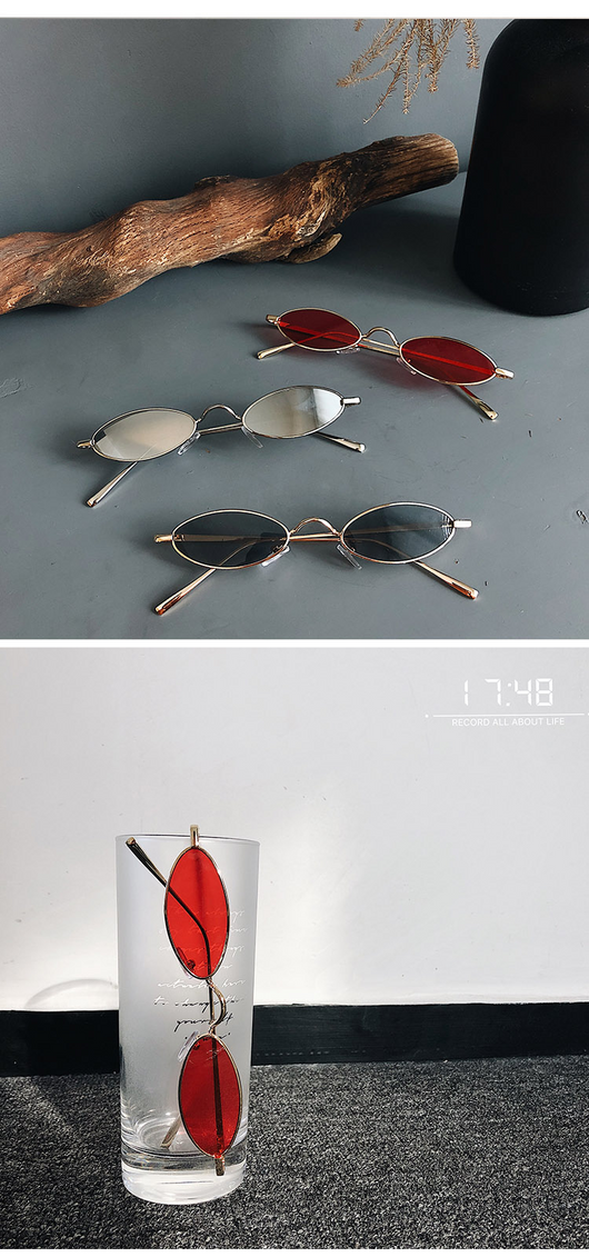 Silver-framed oval sunglasses with dark lenses reflecting a warm-toned object, displayed on a white tray. - Image 13