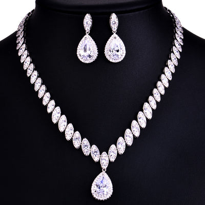 Silver-toned necklace and earring set with red teardrop stones and clear marquise-cut accents on a black display. - Image 7
