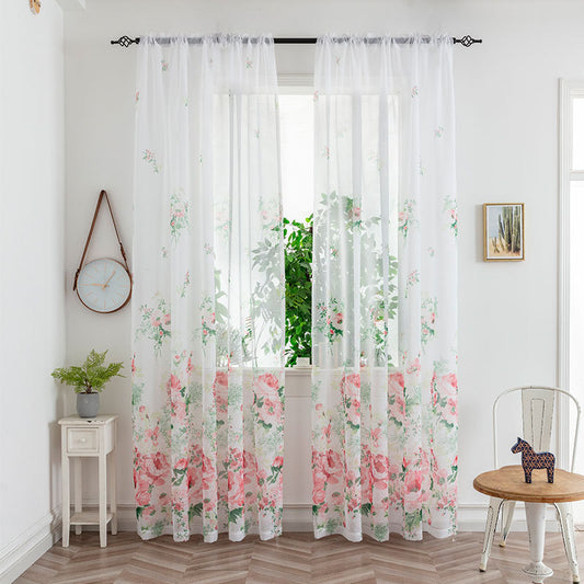 Sheer white mesh curtains with purple and light blue floral patterns, hung on a black rod in a bright room.