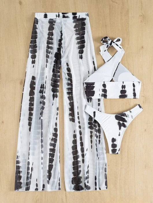 Woman in a white and blue tie-dye three-piece swimsuit set, featuring a halter bikini top, bottoms, and mesh cover-up pants. - Image 5